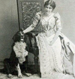 Photo en noir et blanc, Eunice Newton Foote assise sur un fauteuil en bois avec un grand dossier accompagnée d'un chien assis à sa droite. Un grand chien au pelage noir et blanc.